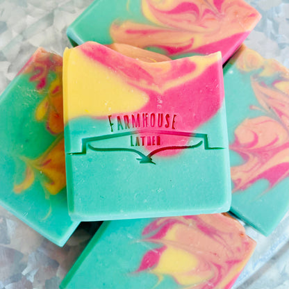 Marbled soap bar in teal, pink, and yellow with Farmhouse label on front.