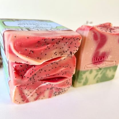 Stacked watermelon goat milk soap bars with black specks and red-pink faces