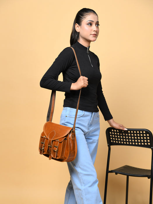 Brown leather sling bag with front flap, buckle details, and long adjustable strap
