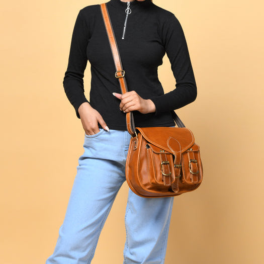 Brown leather sling bag for women worn crossbody, with flap and front pocket straps