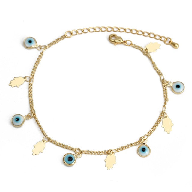 Charm bracelet with gold chain, blue evil-eye drops, and leaf/heart charms