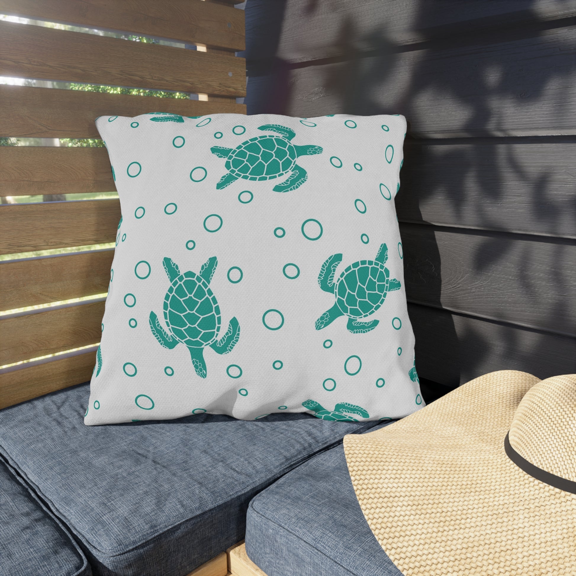 Outdoor sea turtle pillow on patio seat, white with teal turtles and circle pattern