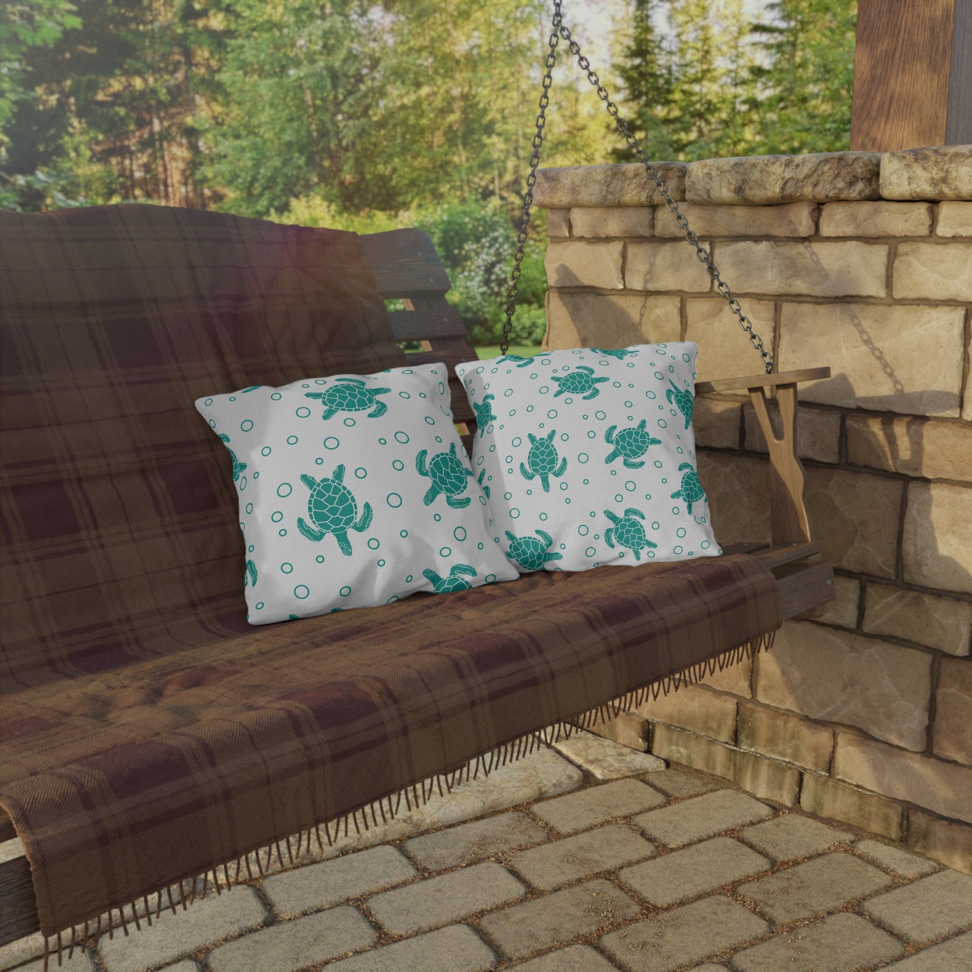 Two outdoor throw pillows with teal sea turtle and circle-dot pattern on white fabric.