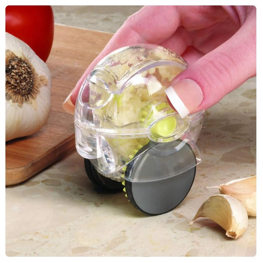 Handheld rolling garlic chopper with clear body, black base, and green cutting blades