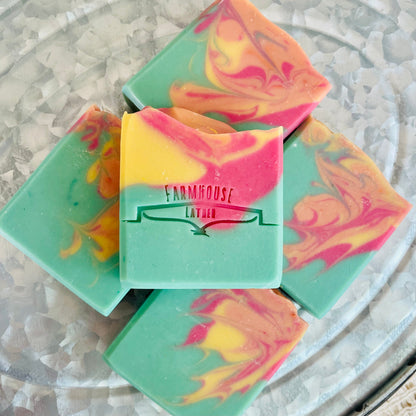 Stack of marbled soap bars in teal, pink, and yellow with Farmhouse label on front.