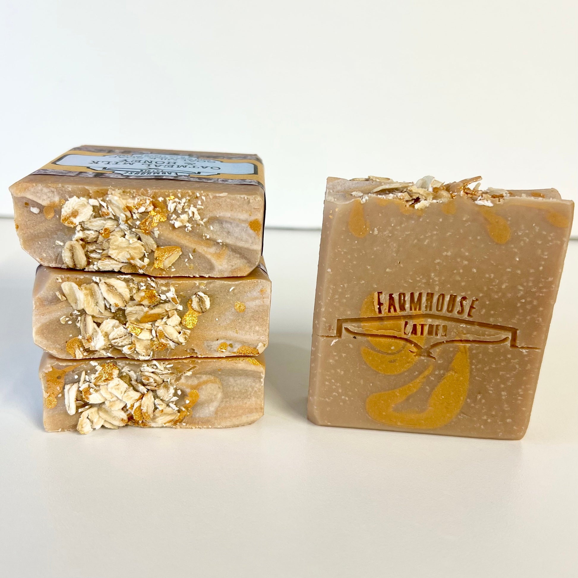 Goat milk soap bar with honey-colored specks and oat flakes, square shape