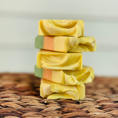 Stacked soap bars with yellow top and green-orange layers, textured surface