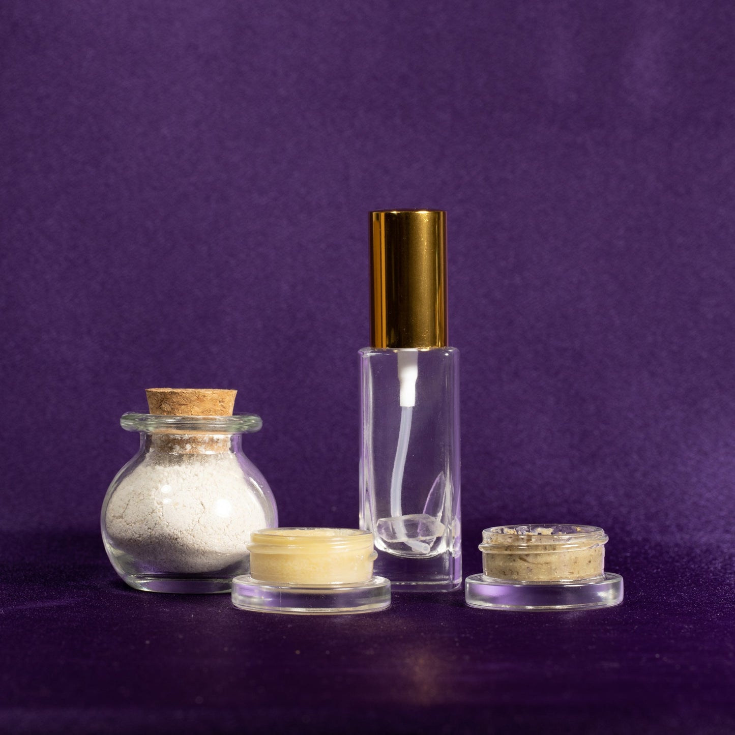 Skincare container set with clear bottle, gold-capped jar, and small tins