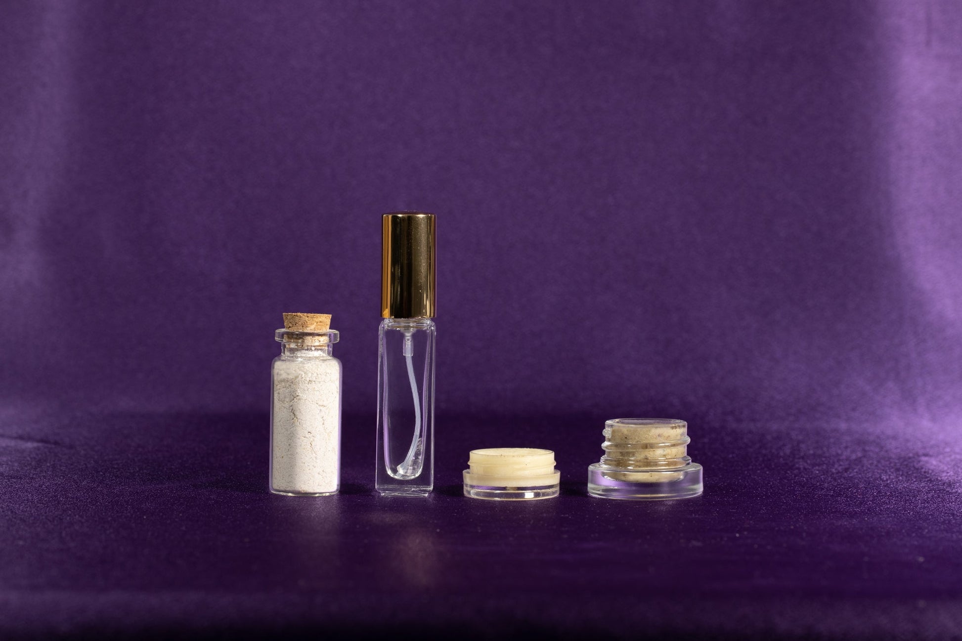 Skincare glow set with clear bottle, gold cap, white powder jar, and small cream jars