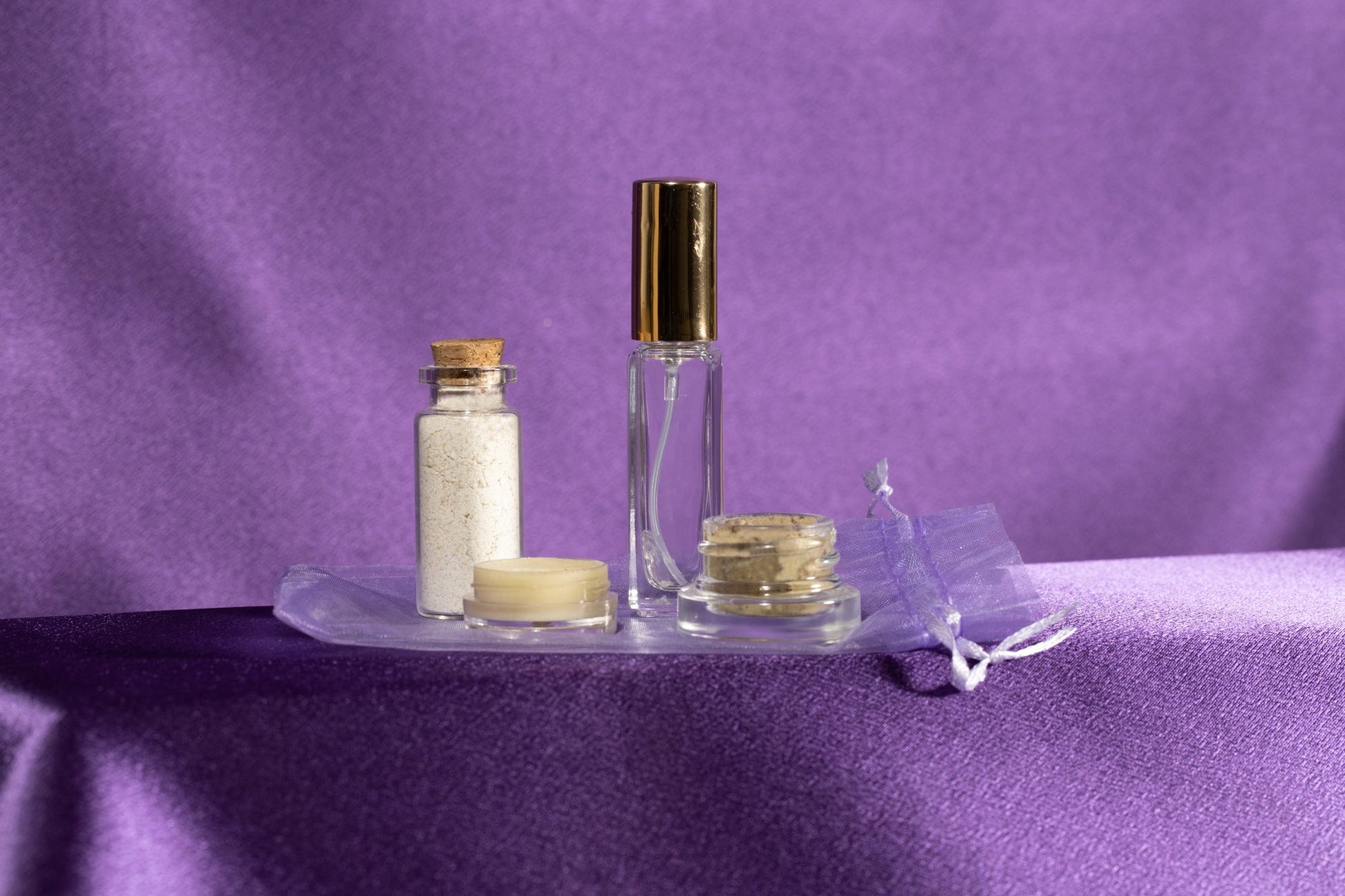 Skincare glow set with clear bottle and gold cap, white jar, and small cream jar