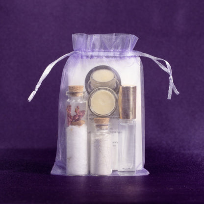 Clear drawstring gift pouch containing glass bottles, salt jars, and cream in jars