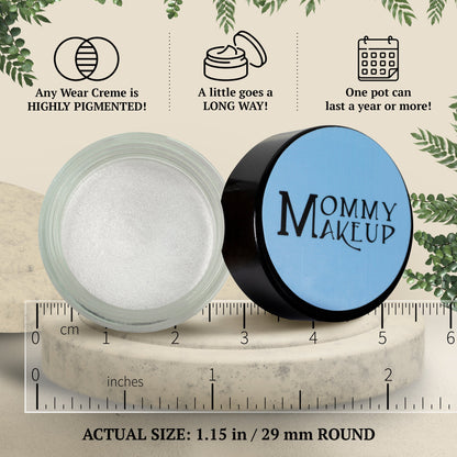 Shimmering white cream-to-powder makeup jar and black lid next to measurement marks