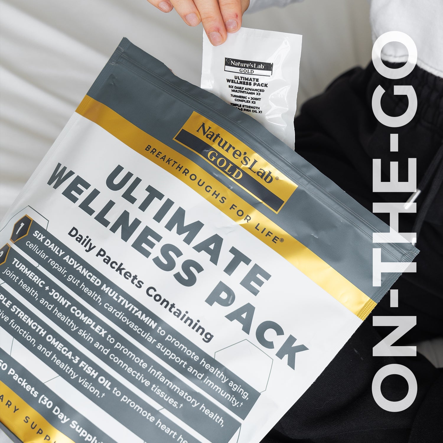 Wellness Pack supplement pouches in hand with gold band and dark green logo label