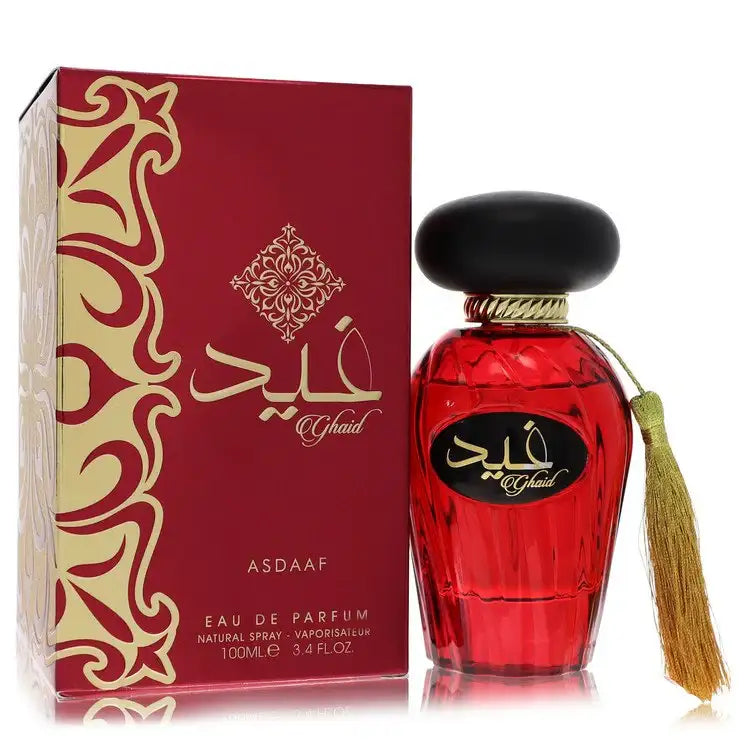 Red perfume bottle with black cap and gold tassel beside burgundy box with gold arabesque