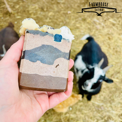 Handmade soap bar with blue top accents and white swirl frosting detail