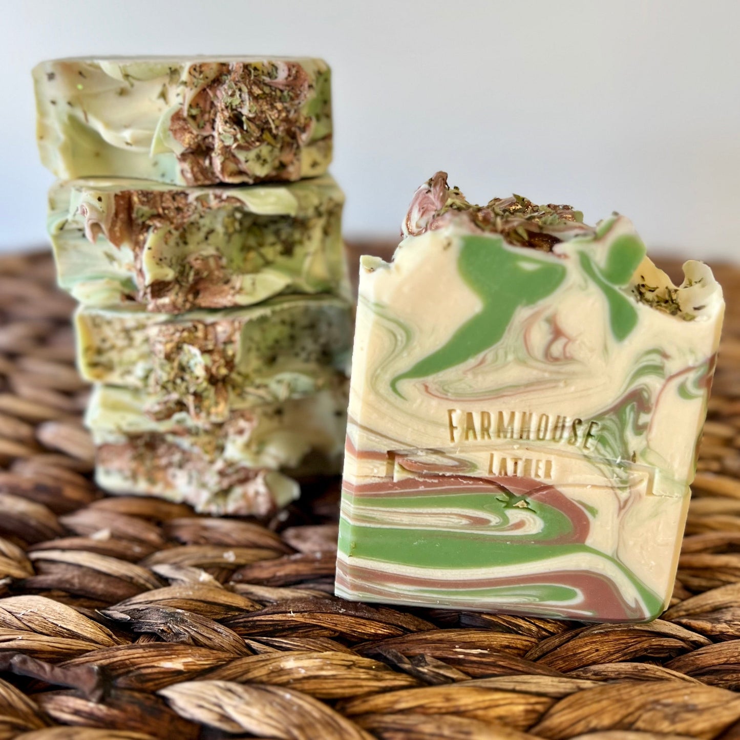 Marbled soap bar in cream, green, and brown on a woven mat