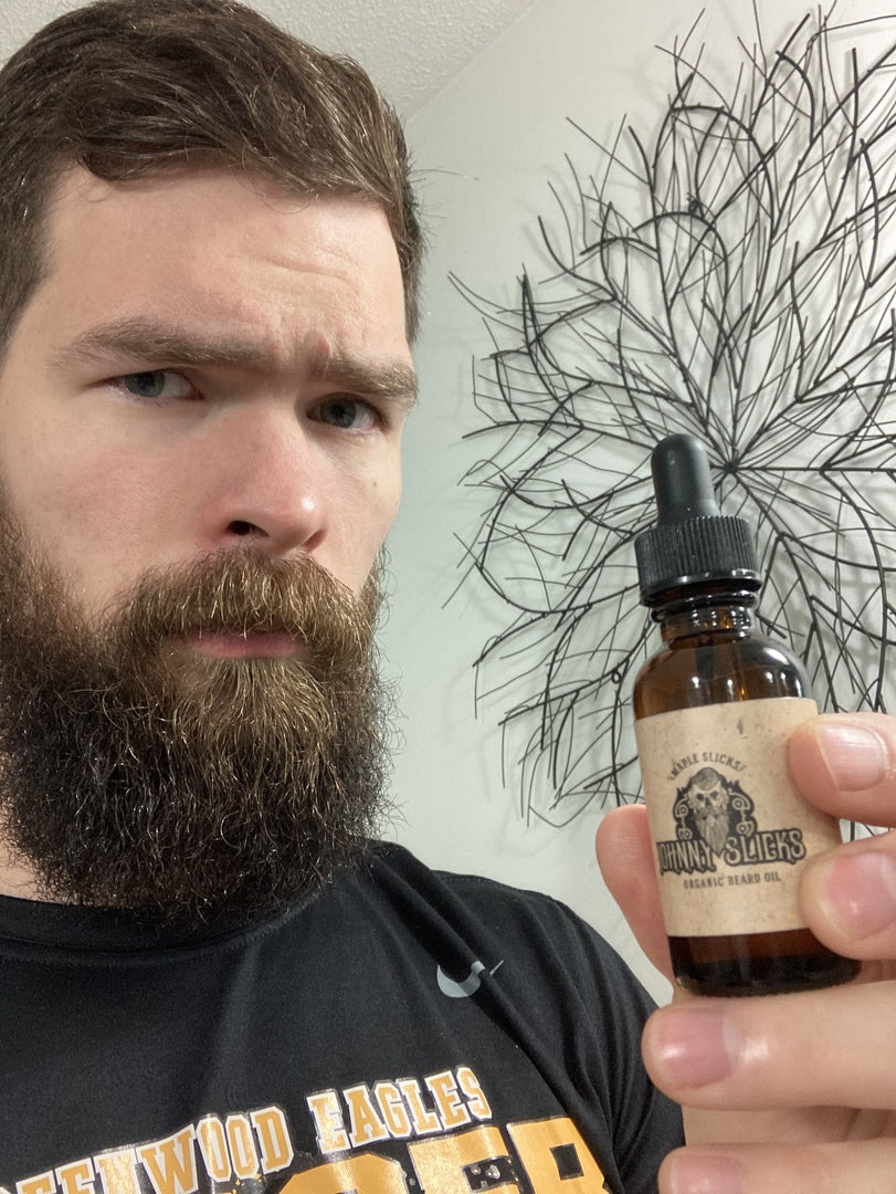 Man holding Organic beard oil bottle, amber glass and black dropper.