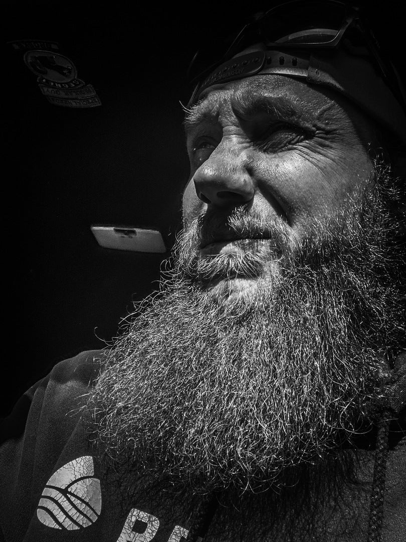 Organic beard oil; bearded man with long beard and dark cap, side view