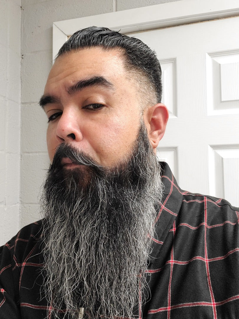Beard oil grooming on a long dark beard, man with full beard.
