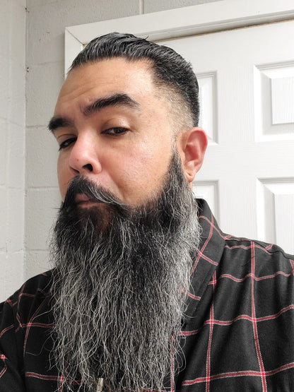 Beard oil grooming on a long dark beard, man with full beard.