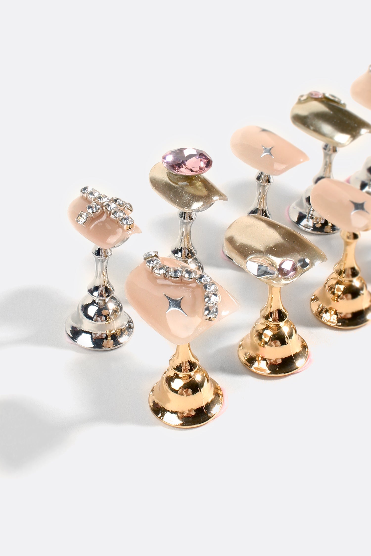 Close-up of gold and silver rhinestone gel nail tips with nude panels and pink gems