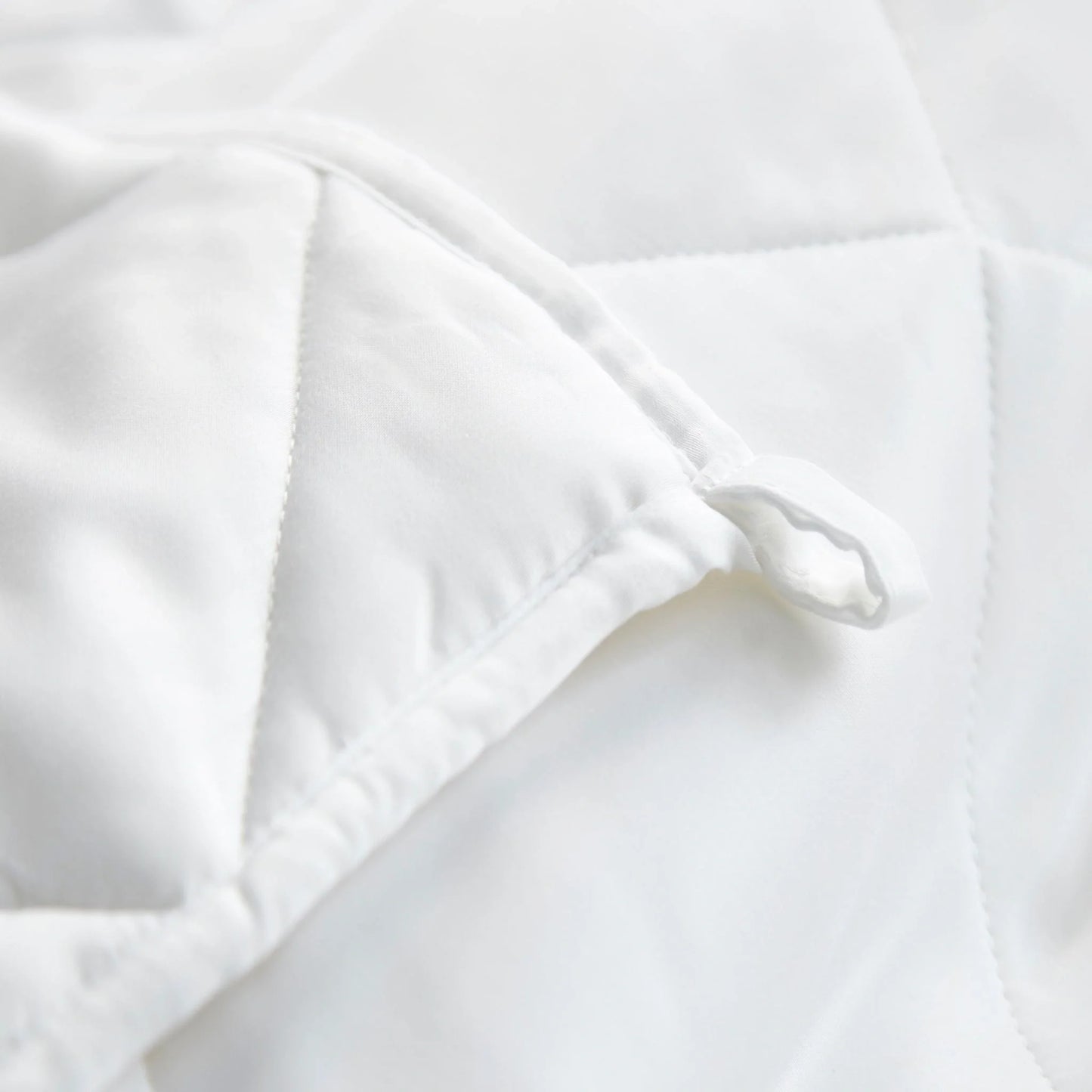 White duvet comforter corner close-up with stitched edge and inner baffling