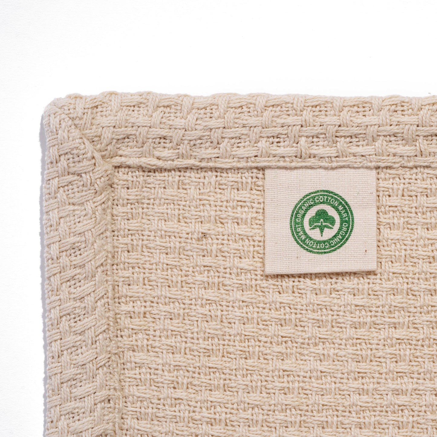 Beige basket-weave blanket corner label with green emblem