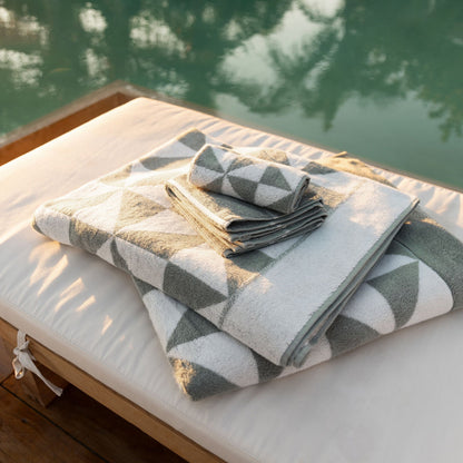 Cotton beach towels folded on a surface, gray-green and white triangle pattern