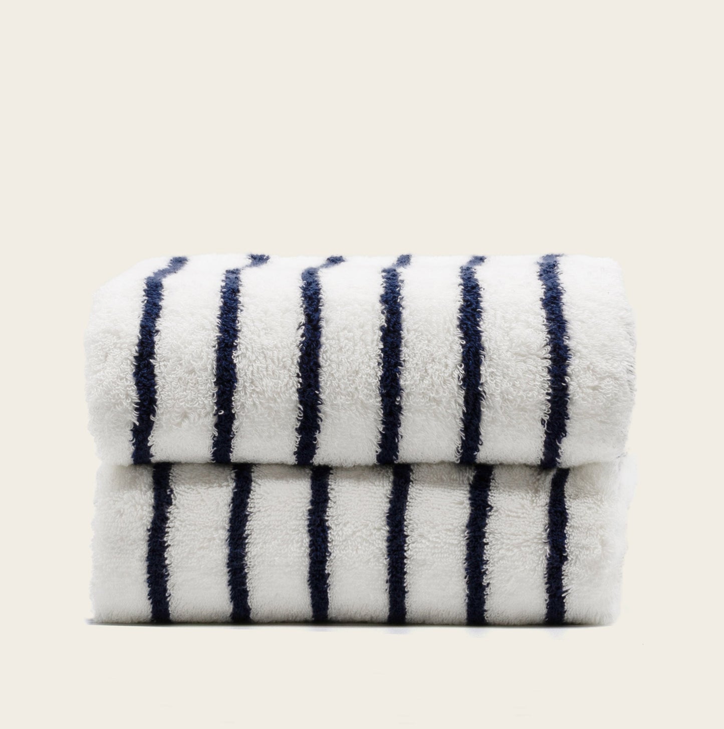 Plush striped towels, white with navy stripes, stacked neatly.