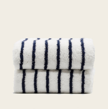 Plush striped towels, white with navy stripes, stacked neatly.