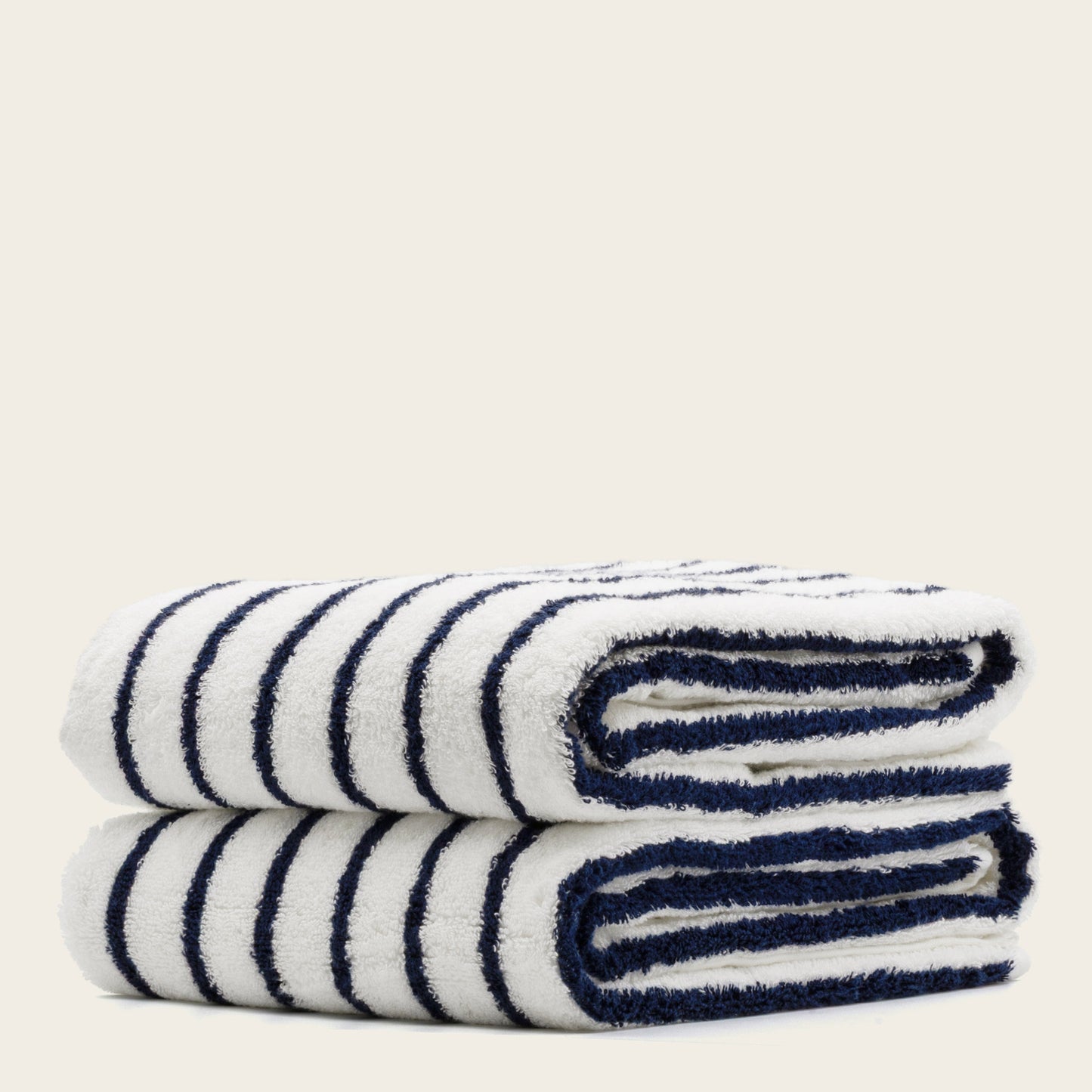 Plush striped hand towels, white with navy stripes, rolled and stacked.