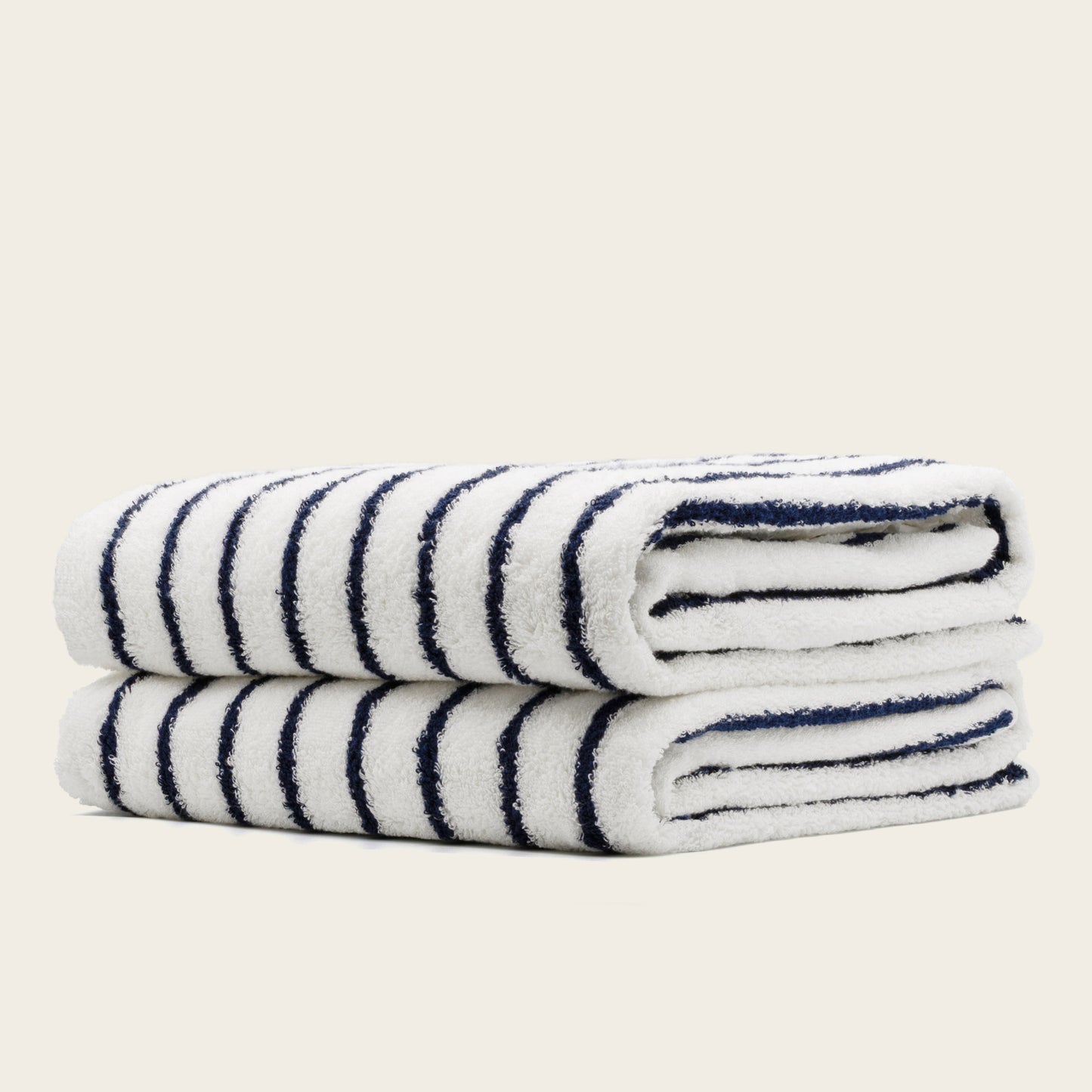 White towels with navy blue stripes, folded rolls with plush terry texture.
