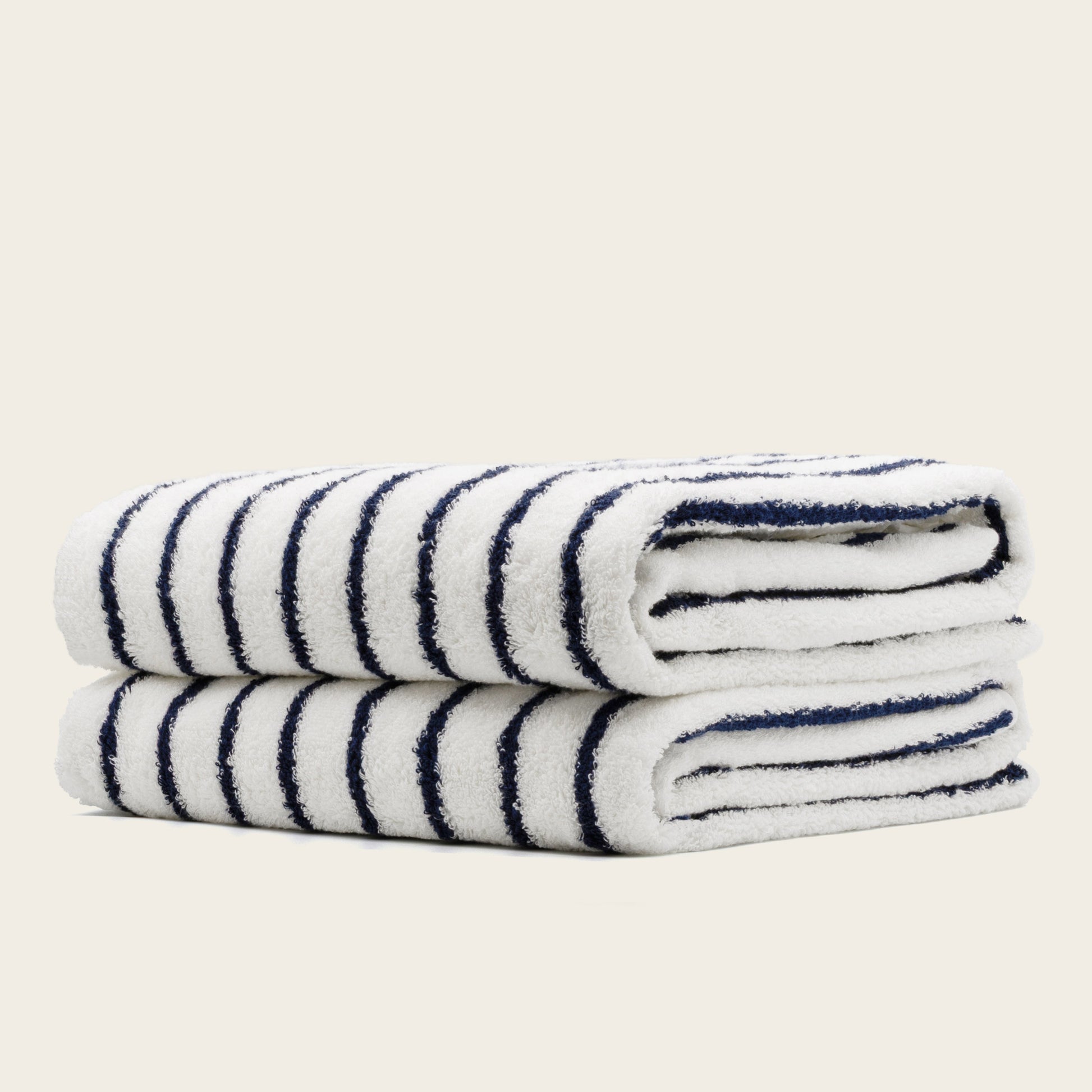 White towels with navy blue stripes, folded rolls with plush terry texture.