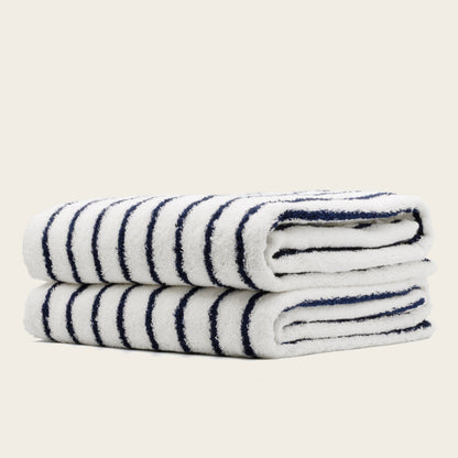 White towels with navy blue stripes, folded rolls with plush terry texture.