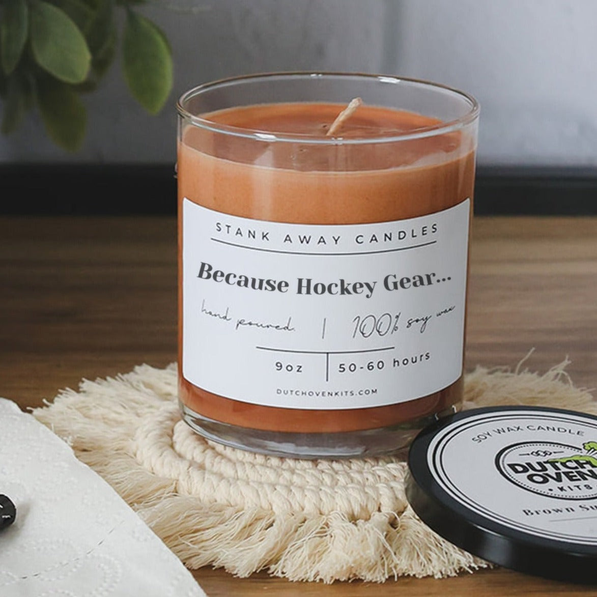 Clear glass soy wax candle with orange wax and printed "Because Hockey Gear" label