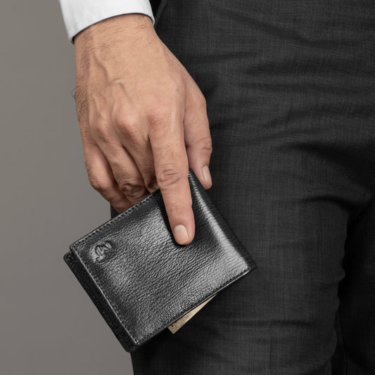 Black leather bi-fold wallet in hand, slim design with embossed logo and stitched trim