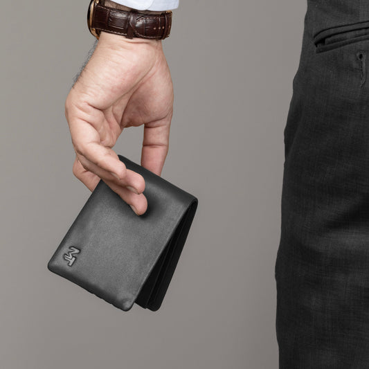 Black leather billfold wallet held in hand, slim profile