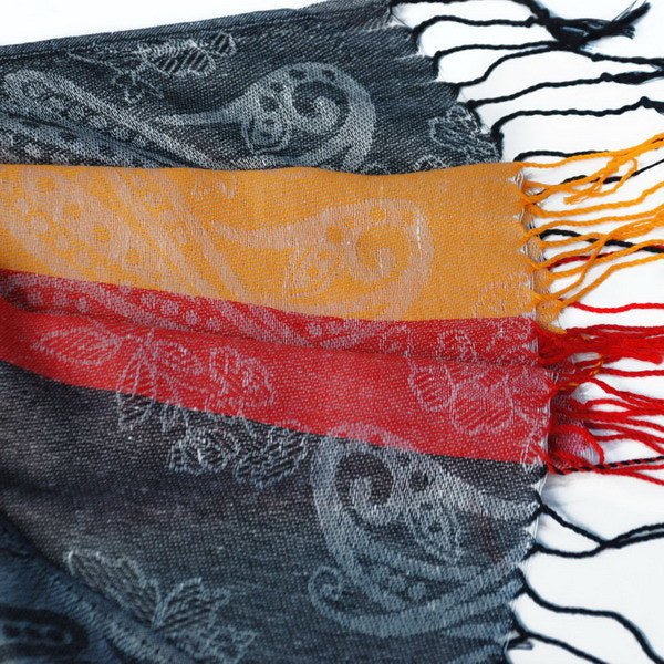 Gray paisley pashmina scarf close-up with orange and red stripe band and fringed edge