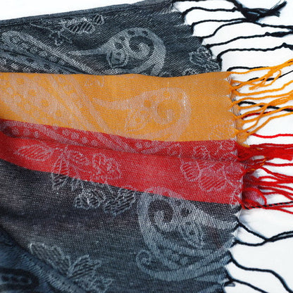Gray paisley pashmina scarf close-up with orange and red stripe band and fringed edge