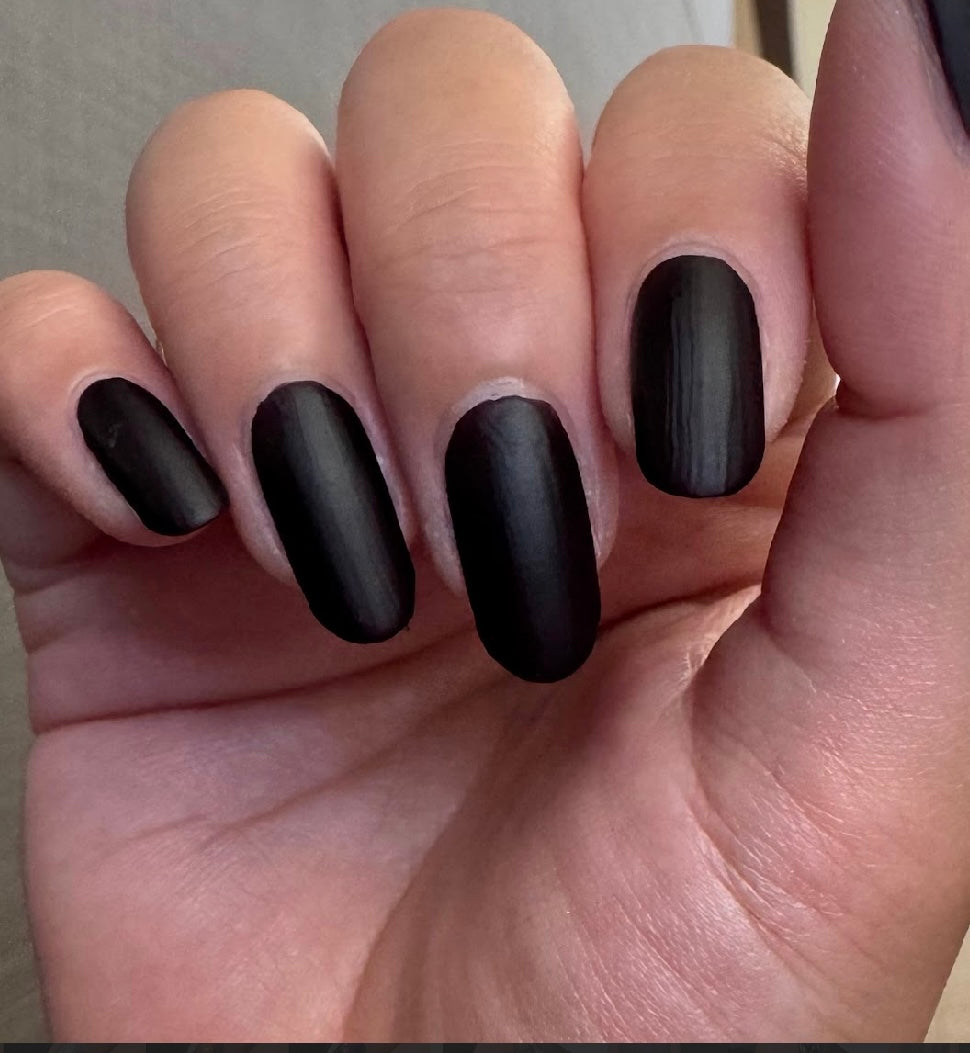 Hand with matte dark nail polish, five oval nails