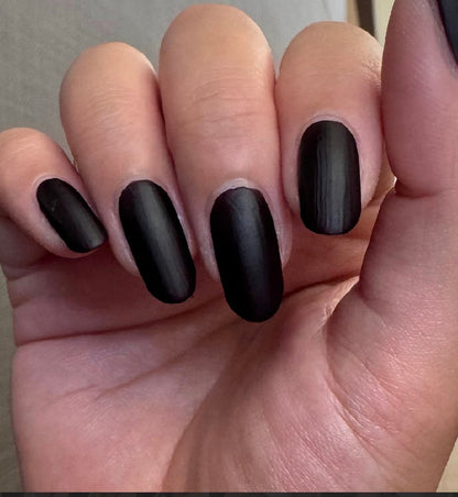 Hand with matte dark nail polish, five oval nails