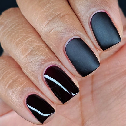 Hand with matte dark and glossy dark nail polish, square-to-oval tips