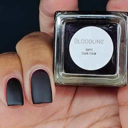 Nail polish bottle labeled Bloodline, 15ml, dark elixir, held in hand