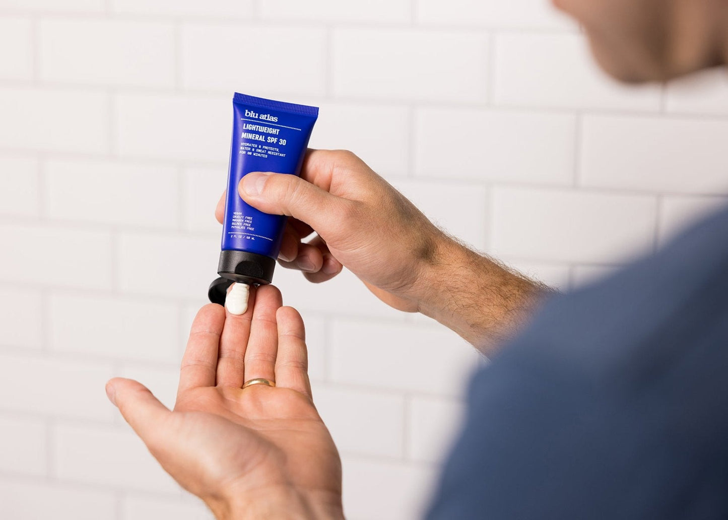 Lightweight mineral SPF 30 sunscreen tube in hand, black nozzle