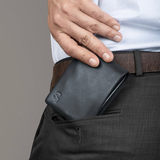 Blue leather billfold wallet with snap closure, held in hand