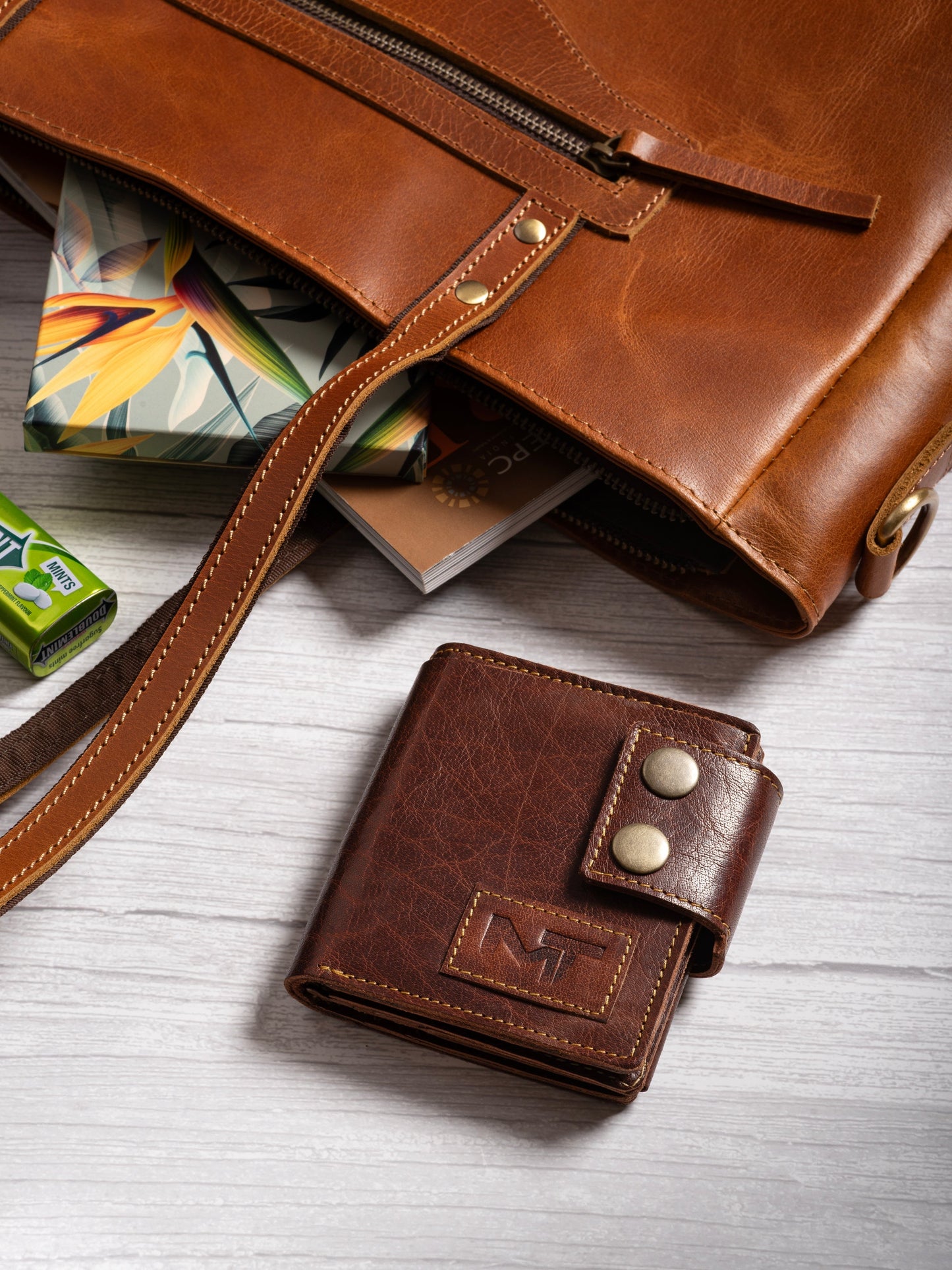 Brown leather snap wallet with MT emblem, shown with zipper pouch and cards