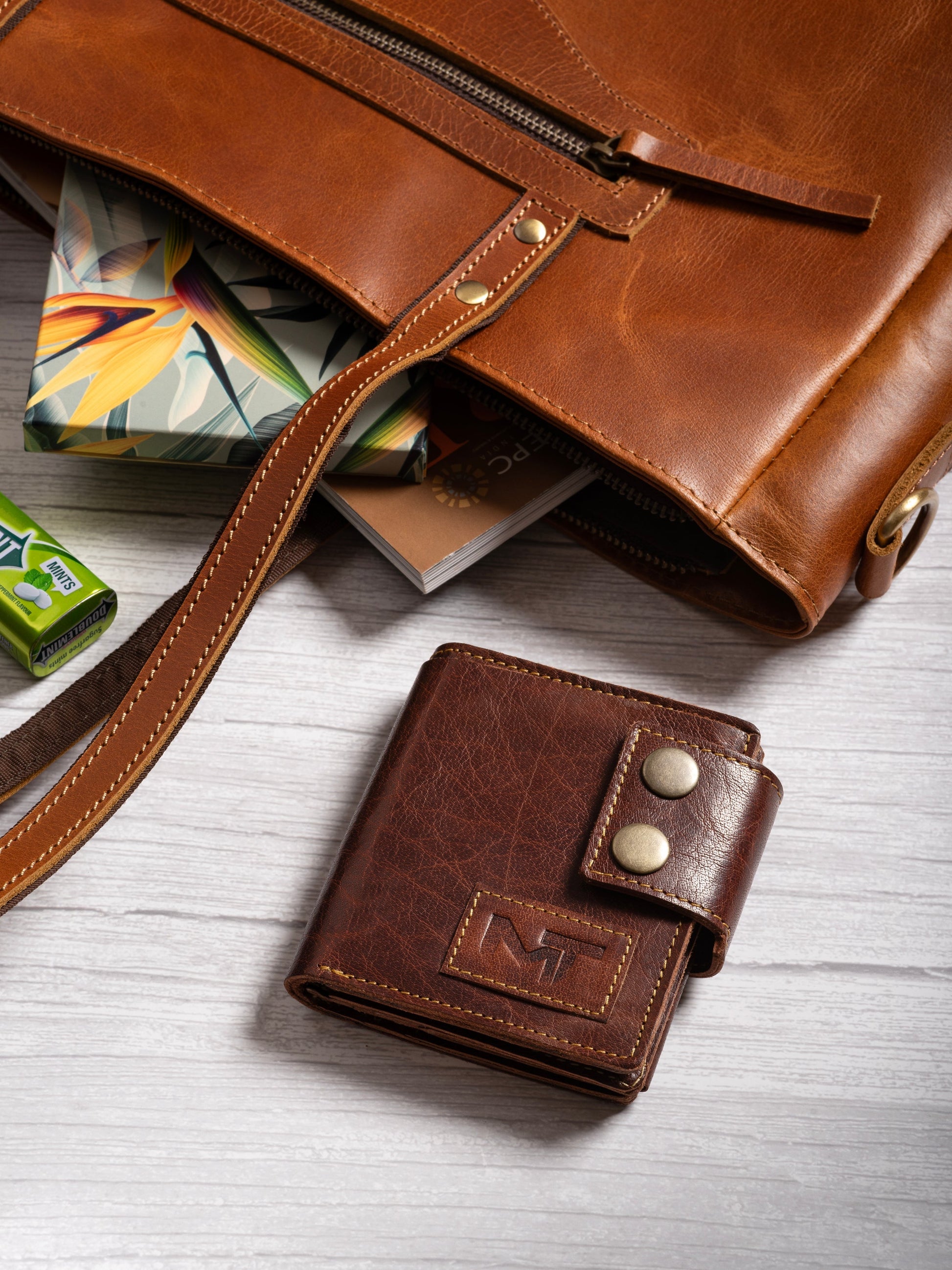 Brown leather snap wallet with MT emblem, shown with zipper pouch and cards