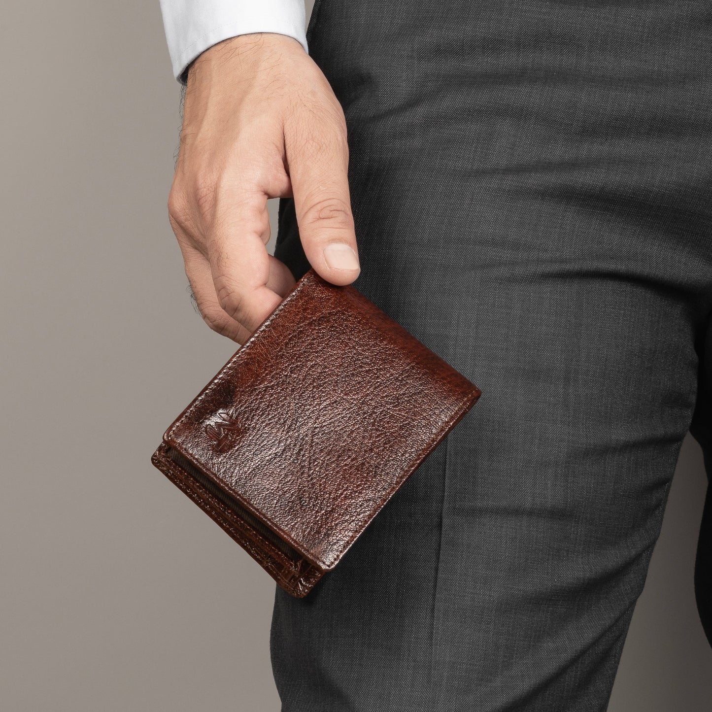 Brown leather sleek wallet held in hand, front view with visible logo.