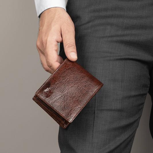 Brown leather sleek wallet held in hand, front view with visible logo.