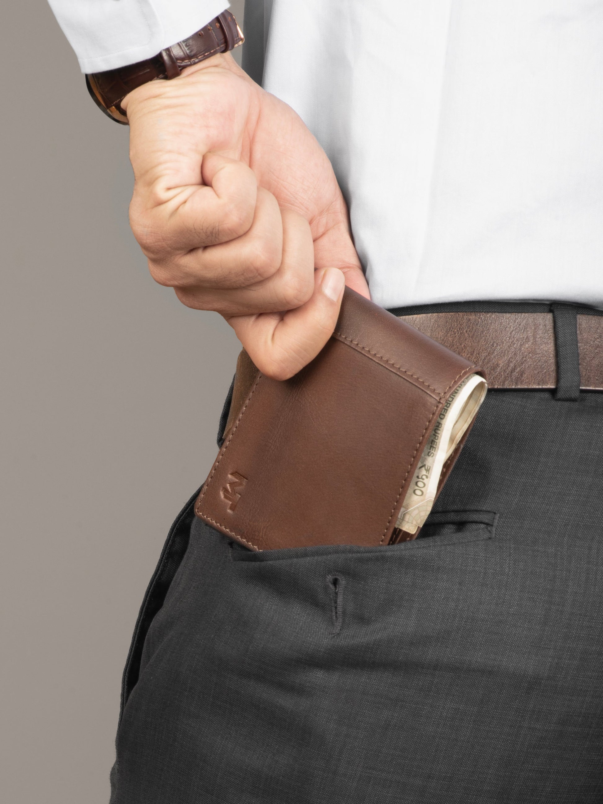 Brown bi-fold leather wallet partially tucked into a back pocket